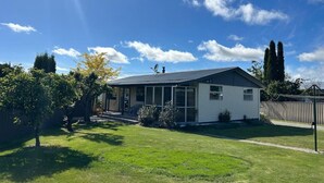A single-story house with a covered porch, a satellite dish, and a well-maintained lawn. - Twizel Tranquility, FREE Wi-Fi (Twizel)