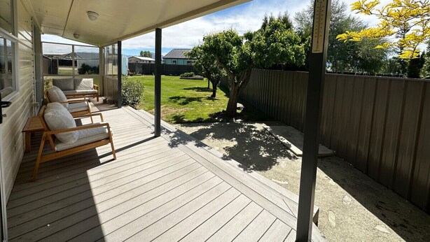 A covered patio with wooden flooring and a view of a backyard with a wooden fence and trees. - Twizel Tranquility, FREE Wi-Fi (Twizel)