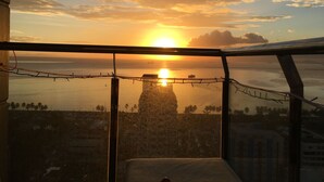 A balcony with a view of the sunset over the sea, a barbed wire fence, and a distant ship. - Manila Bayview Rental Luxury 3BR 3BA Condo w/Balcony Sunset View Pool Kitchen (Manila)