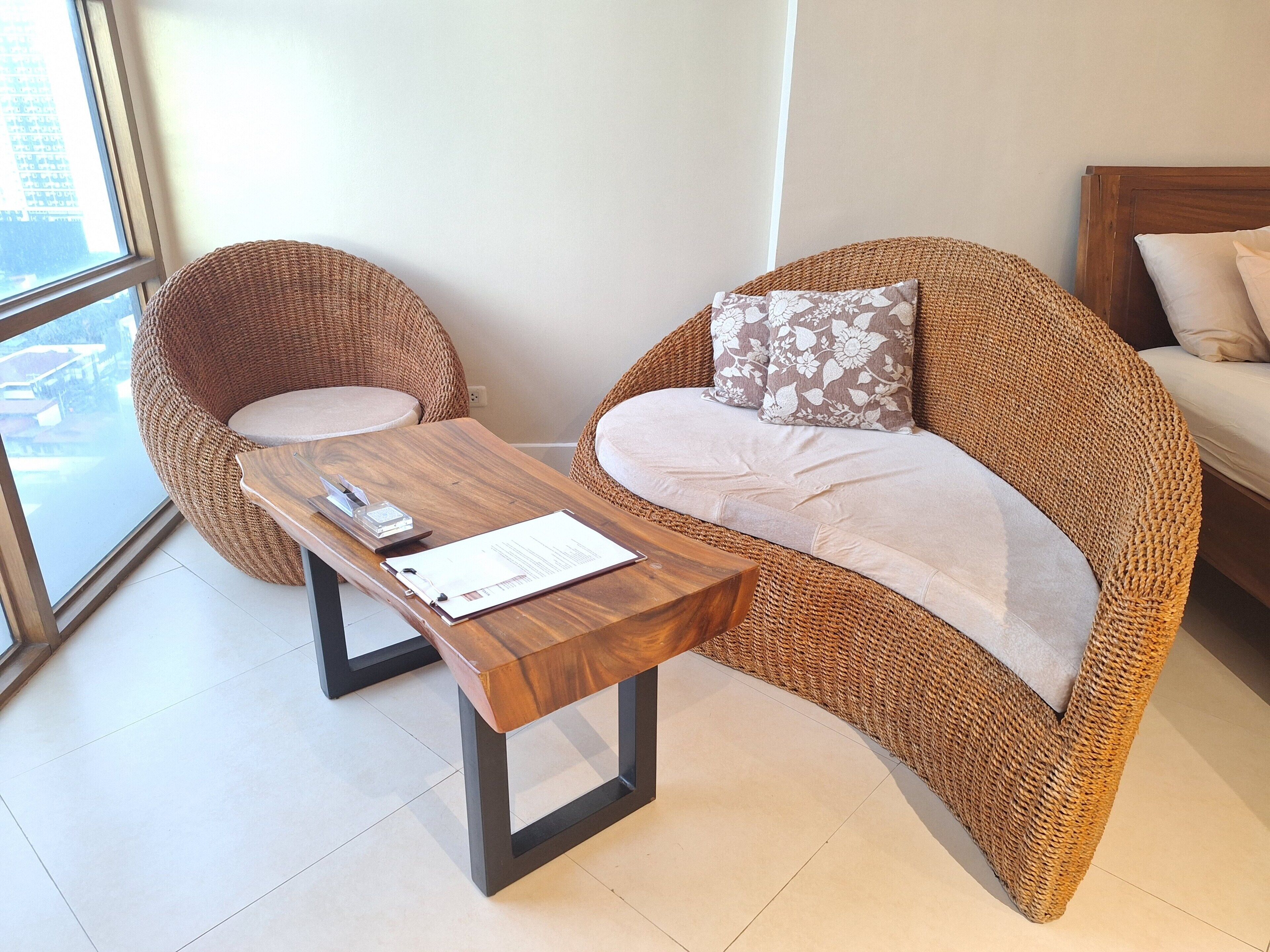 Una habitación con muebles de mimbre, una mesa de madera y una cama.