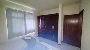 A bedroom with a bed, a wardrobe, and a window with curtains.