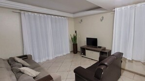 A living room with a sofa, a TV stand, and curtains.