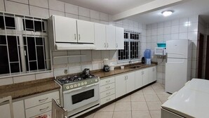 A kitchen with white cabinets, a stove, a microwave, and a refrigerator.