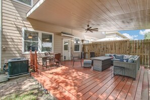 Eine überdachte Terrasse mit Gartenmöbeln, einem Deckenventilator und einer Klimaanlage.