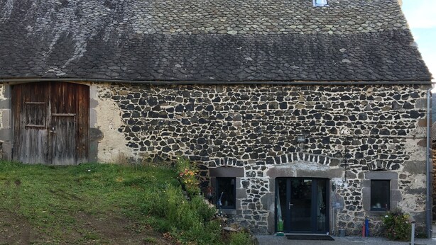 A stone building with a weathered wooden door and a chimney.
