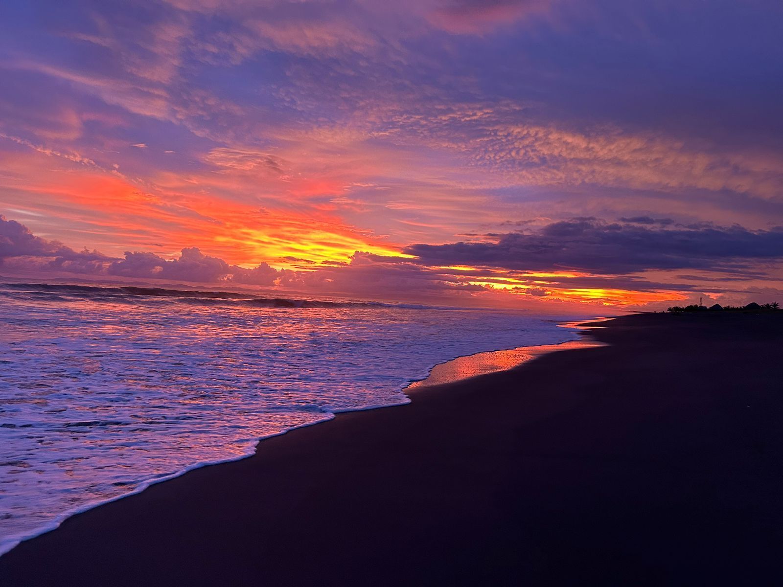 Een strand bij zonsondergang met golven en een heldere lucht.