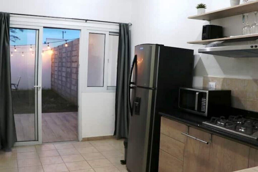 Cocina compacta con refrigerador, microondas y estufa a gas.