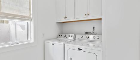A laundry room with two white washing machines and a stove.