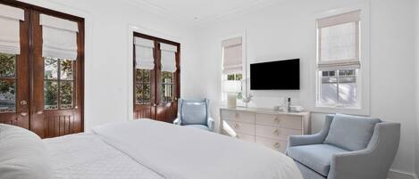 Een slaapkamer met een groot bed, een aan de muur bevestigde televisie, een dressoir en een stoel.