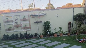 A paved patio with a geometric pattern, surrounded by potted plants and a low wall. - Jardim das Orquídeas 1 (Rio das Ostras)