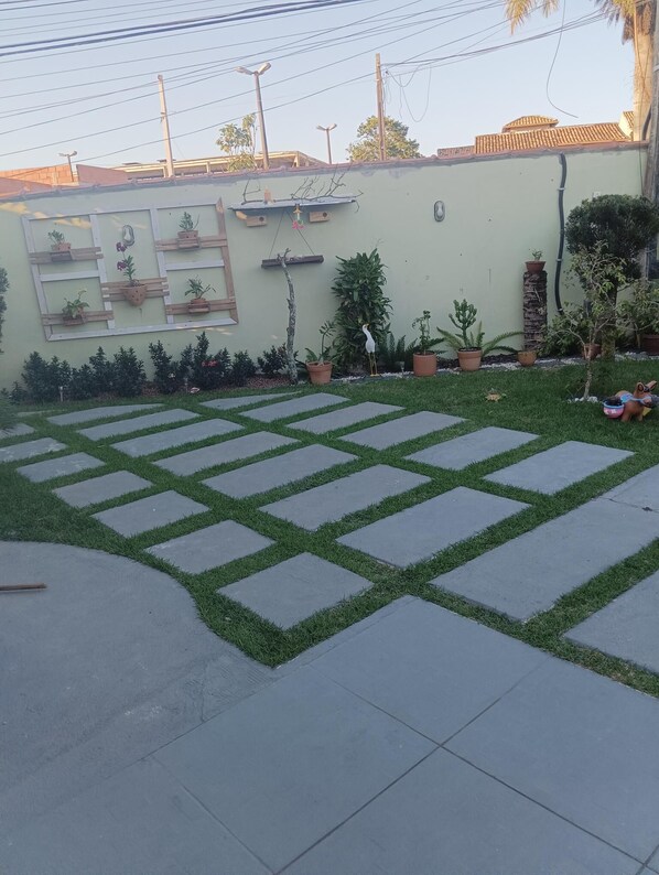 Eine gepflasterte Terrasse mit geometrischem Muster, umgeben von Kübelpflanzen und einer niedrigen Mauer.