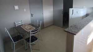 A small kitchen with a dining table, chairs, a ceiling fan, and a refrigerator. - Jardim das Orquídeas 1 (Rio das Ostras)