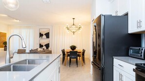 A modern kitchen with a central island, stainless steel appliances, and a dining area with a chandelier. - 2994 - Great Family Home near Disney, private pool, Storey Lake Resort (Kissimmee)