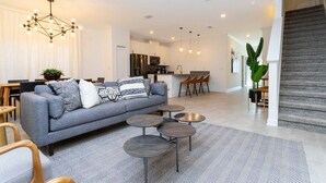 A modern living room with a grey sofa, round coffee tables, and a herringbone-patterned rug. - 2994 - Great Family Home near Disney, private pool, Storey Lake Resort (Kissimmee)