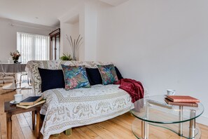 A modern living room with a sofa, a glass coffee table, and a dining area with a table and chairs. - Bright & Spacious 2-Bedroom House (Oxford)