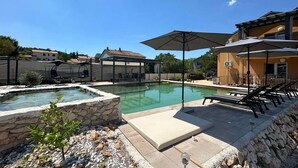 A swimming pool with lounge chairs and umbrellas, surrounded by stone walls and potted plants. - 2 bedroom cozy apartment in Krsan (Krsan)