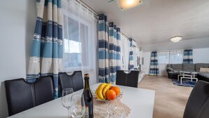 A dining area with a table set for two, featuring a bottle of wine, two wine glasses, and a fruit bowl with bananas and oranges. - 2 bedroom cozy apartment in Krsan (Krsan)