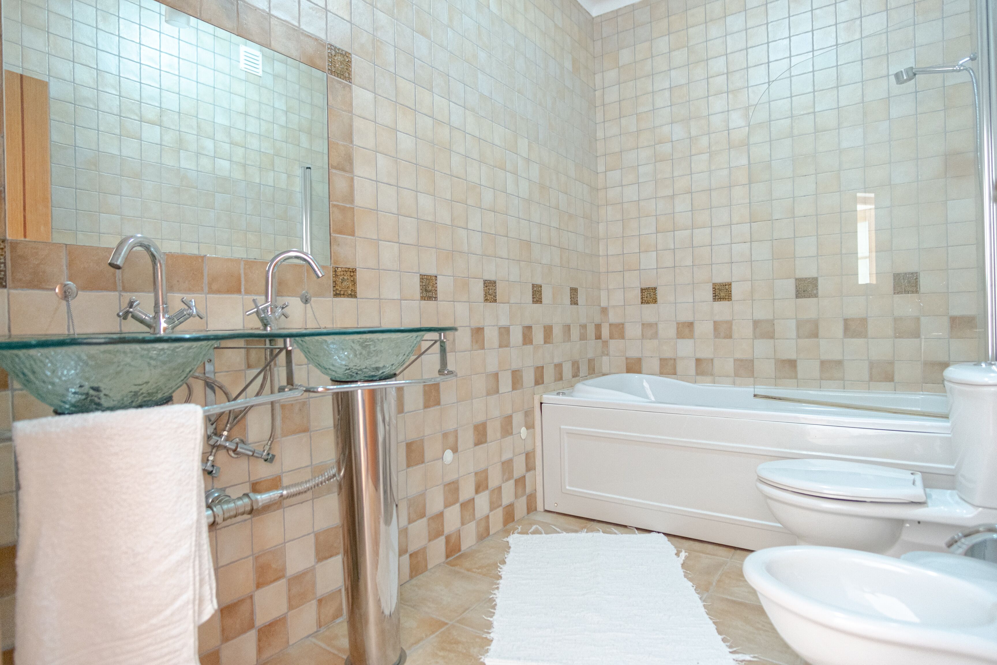 Ein Badezimmer mit einem Glaswaschbecken, einer Badewanne und einer Toilette.