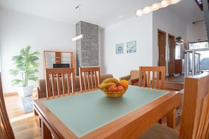 A dining area with a table, chairs, a fruit bowl, a potted plant, and a stone wall.