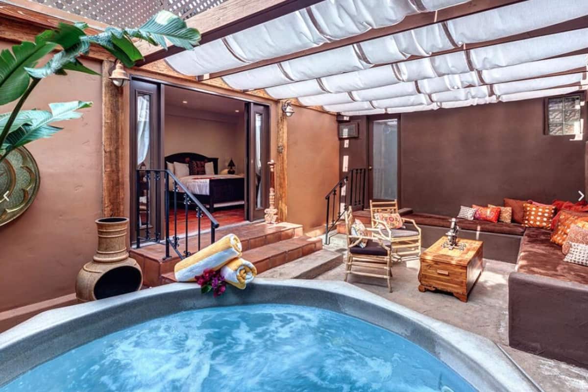 A spa area with a hot tub, seating, and a staircase leading to an indoor room.