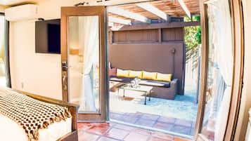 Un dormitorio con una cama, un ventanal corredero que da a un patio con un sofá y una mesa.