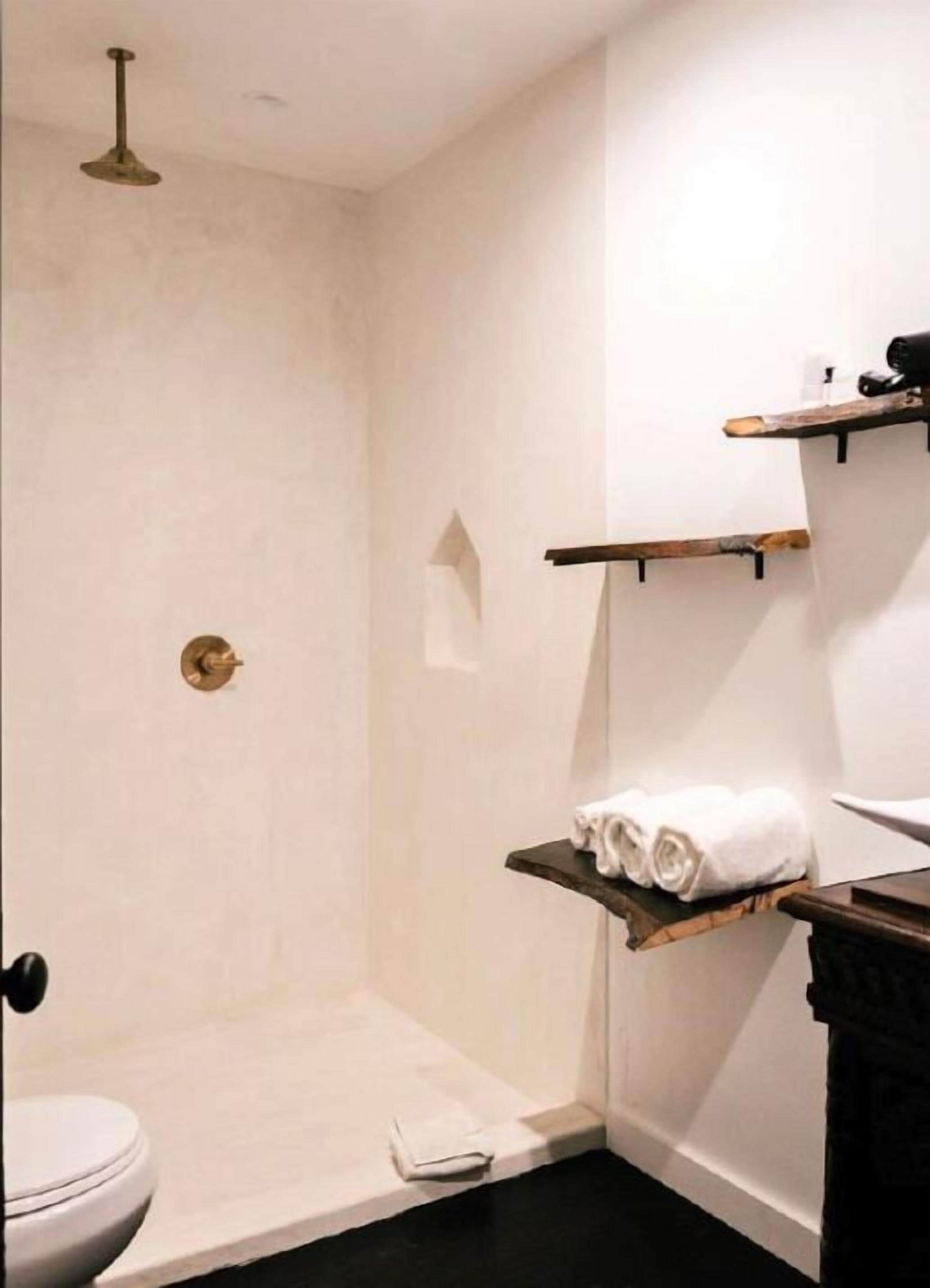 Un bagno moderno con cabina doccia, un water e mensole in legno con asciugamani.