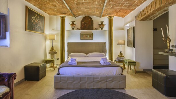 A spacious bedroom with a large bed, a brick ceiling, and a classic design.