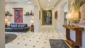 A modern living room with a black leather sofa, a coffee table, and a large abstract painting on the wall.