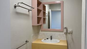 A bathroom with a wooden vanity, a white sink, a pink-framed mirror, and a towel rack.