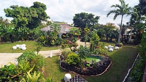 A lush garden with a small pond, seating areas, and a thatched-roof structure. - Coconut Palms Resort & Diamond Casino (Port Vila)