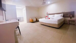 A hotel room with a bed, a desk, a chair, a bedside table, and a wall-mounted TV. - Coconut Palms Resort & Diamond Casino (Port Vila)