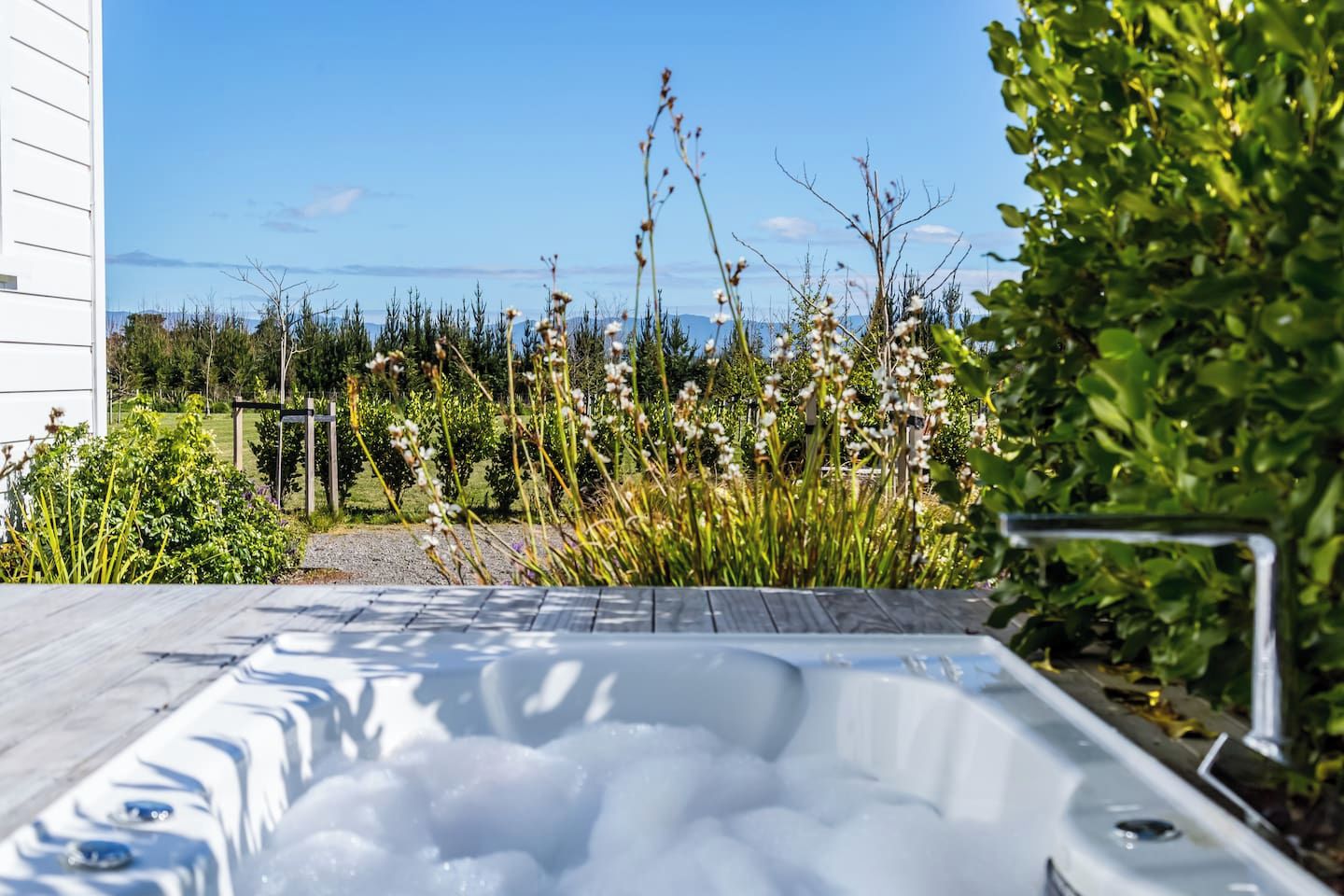 Un jacuzzi con vistas a un jardín y una masa de agua.