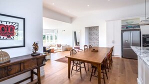 Una cocina amplia con una mesa de comedor de madera, armarios blancos y electrodomésticos de acero inoxidable.