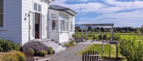 A white building with a covered porch and outdoor seating area.