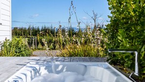 Un jacuzzi con vistas despejadas del jardín circundante y un edificio al fondo.