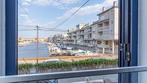 Un port de plaisance avec des bateaux, un ciel dégagé et des immeubles résidentiels en arrière-plan.