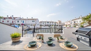 Une terrasse sur le toit aménagée avec un espace repas, comprenant des tables, des chaises et un barbecue.