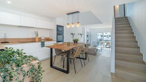 Une cuisine moderne avec un îlot central en bois, des pieds en métal noir et des luminaires suspendus.