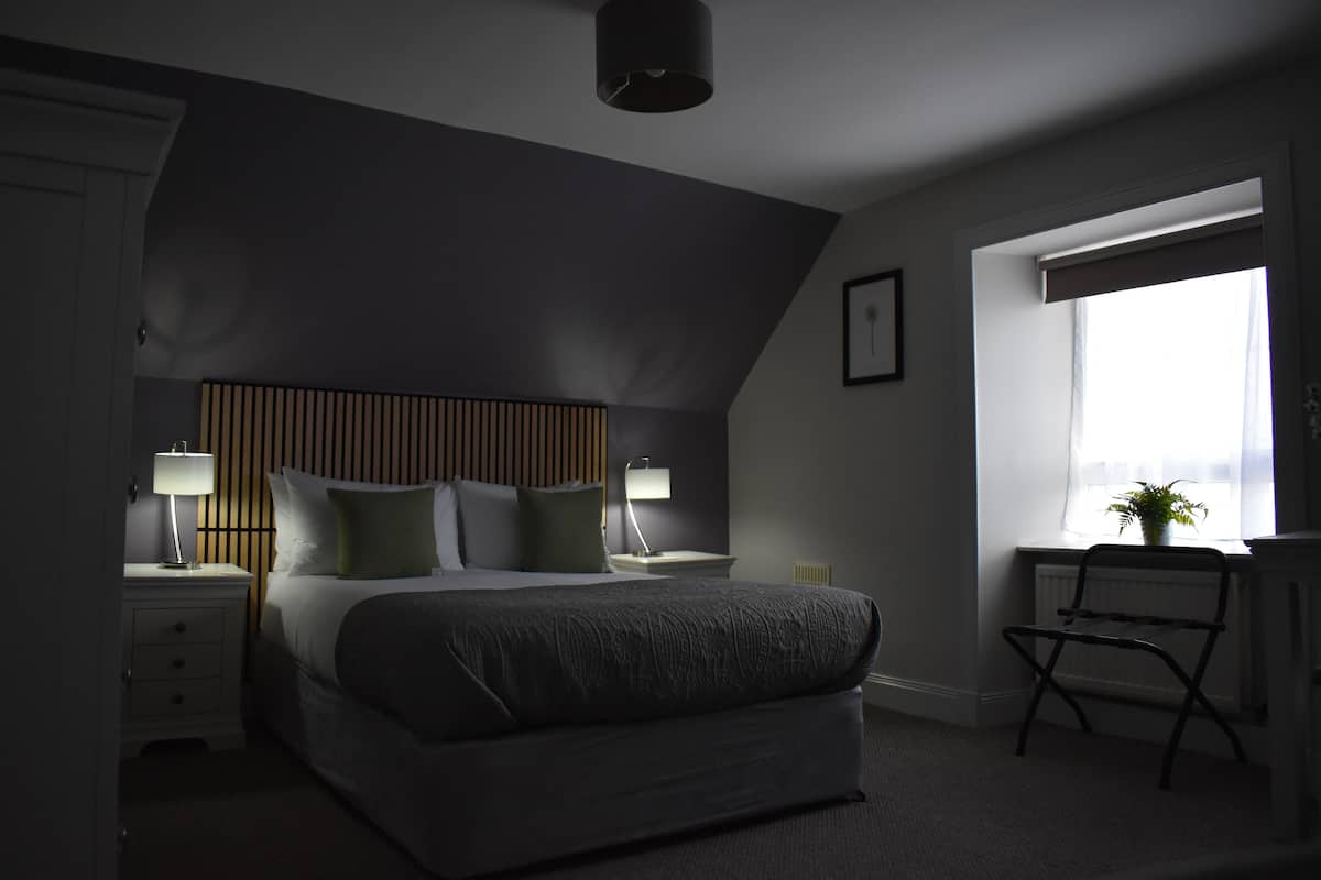 A bedroom with a bed, bedside tables, a chair, and a window.