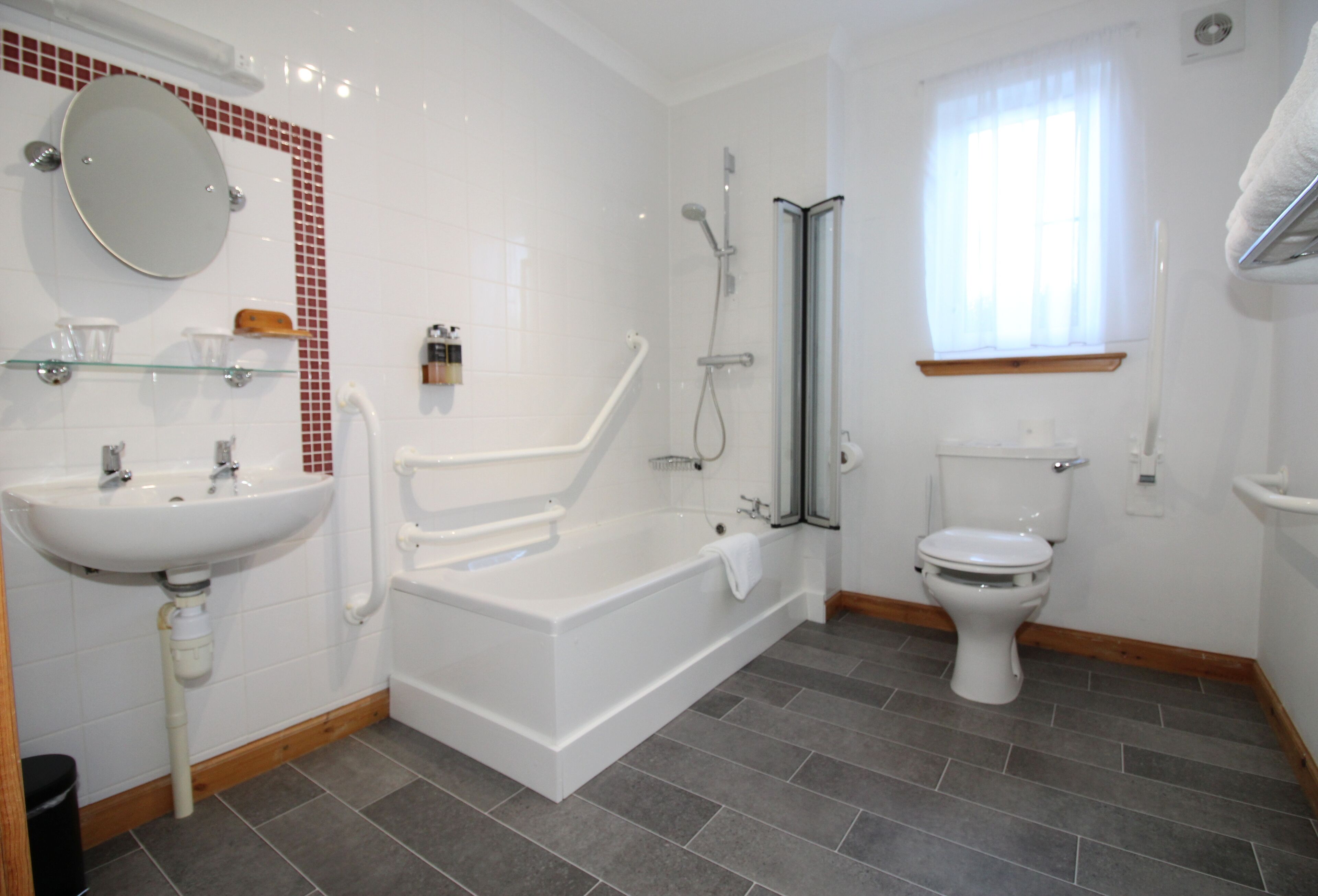 A modern bathroom with a white sink, a bathtub, a toilet, and a shower area.