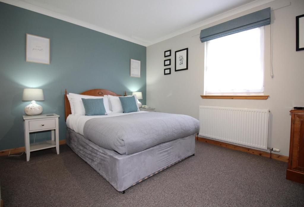 A bedroom with a bed, bedside tables, a window with curtains, and a radiator.