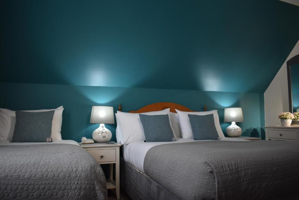 Habitación de hotel con dos camas, mesitas de noche, lámparas y cabecero de madera.