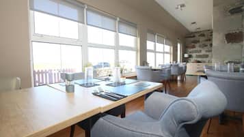 Un comedor con una mesa larga, sillas y vistas a través de ventanas amplias.