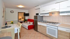 Cocina compacta con armarios blancos, estufa a gas, microondas y refrigerador.