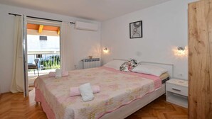 A bedroom with a bed, bedside tables, a radiator, and a view of the outside balcony.