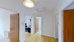 Un couloir avec des portes en bois, un radiateur et un luminaire au plafond.