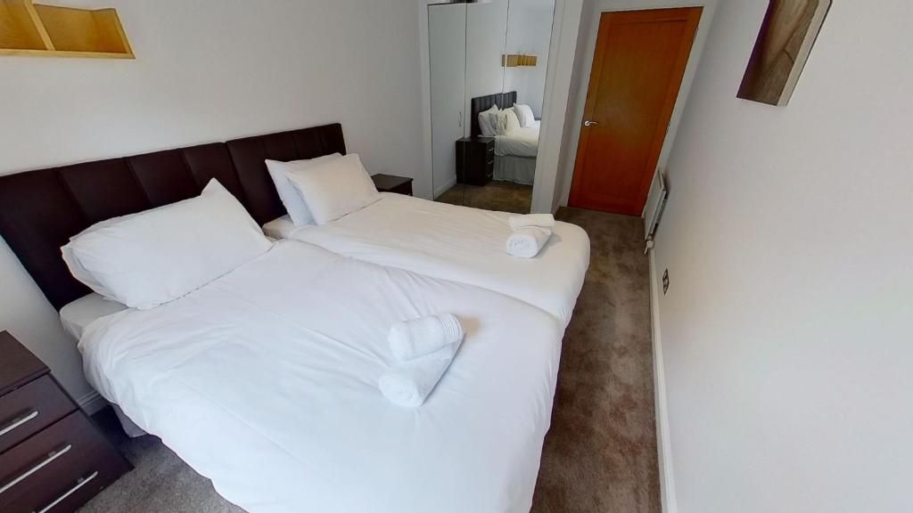 A hotel room with two beds, a wardrobe, a bedside table, and a door.
