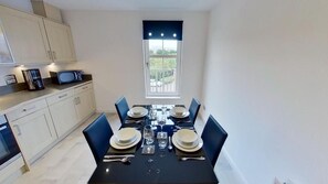 A compact kitchen with a dining area, a window with a view, and a microwave on the counter. - Orange Apartments - 150e Rusbislaw Mansions (Aberdeen)