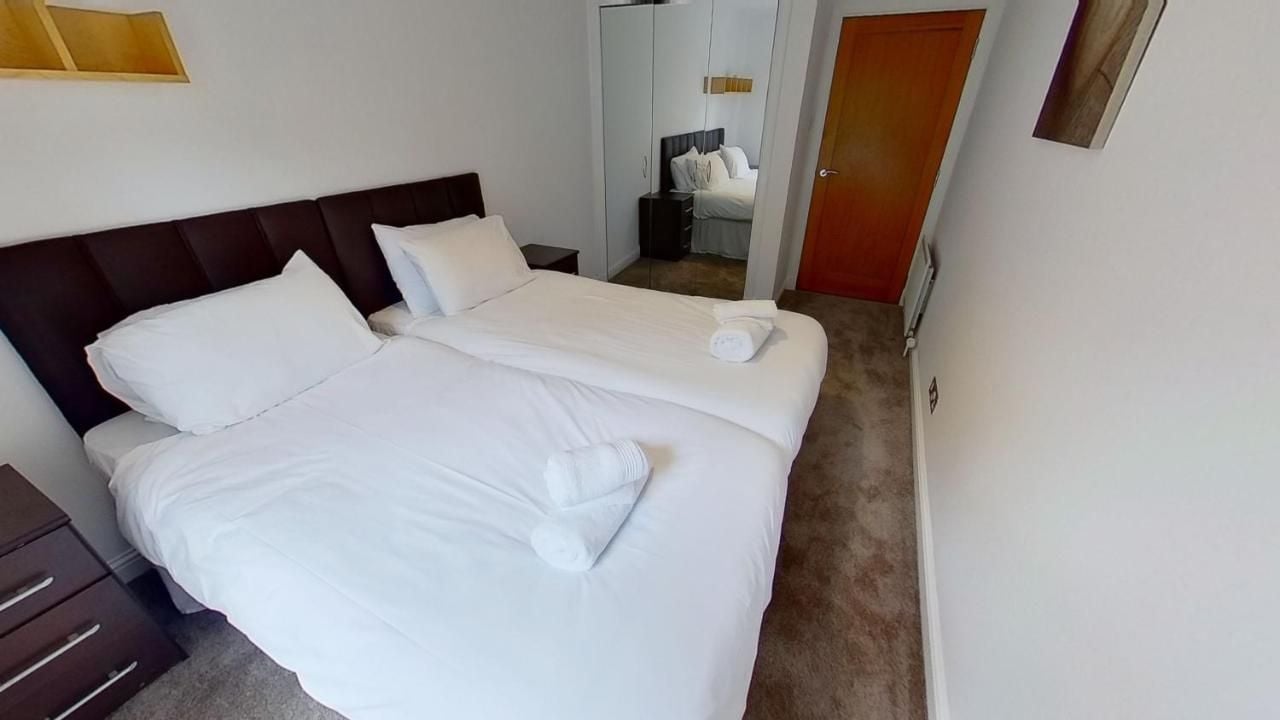 Et hotelværelse med dobbeltseng, et sengebord, et klædeskab og en dør.