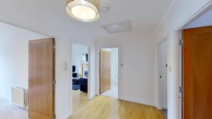 A hallway with wooden doors, a radiator, and a ceiling light fixture. - Orange Apartments - 150e Rusbislaw Mansions (Aberdeen)